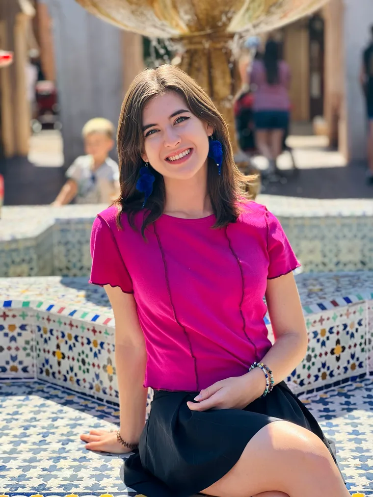 Virginia Kate Brandt in a pink top at a tiled fountain.