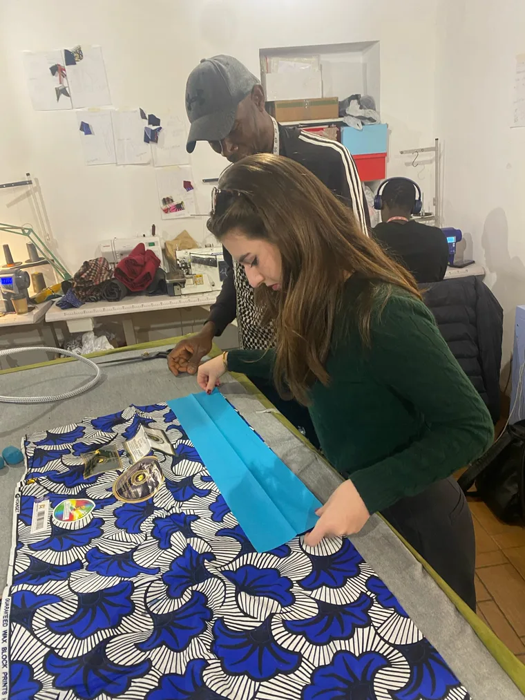 Earnest Alulu and Virginia Kate Brandt cutting blue African wax-print fabric in the Coloriage Laboratorio workroom.